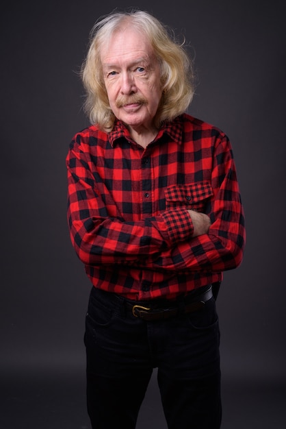 Studio shot of senior man with mustache wearing red checkered shirt against gray background