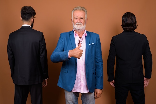 Studio shot of three multi ethnic bearded businessmen together against brown background