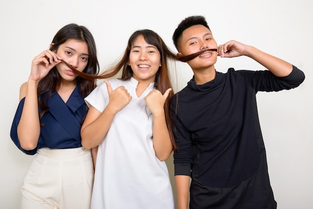 Studio shot of three young beautiful Asian women as friends together against white background