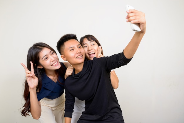 Studio shot of three young beautiful Asian women as friends together against white background