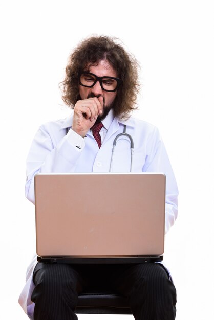 Studio shot of tired man doctor using laptop while yawning