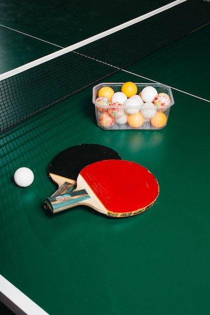 Photo studio shot of two ping pong rackets and a ball are on the green game table