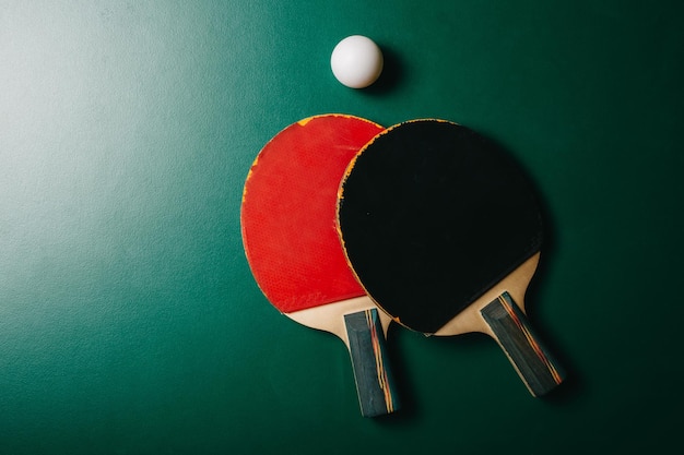 Photo studio shot of two ping pong rackets and a ball are on the green game table