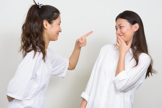 Studio shot of two young beautiful Korean women as friends together against white background