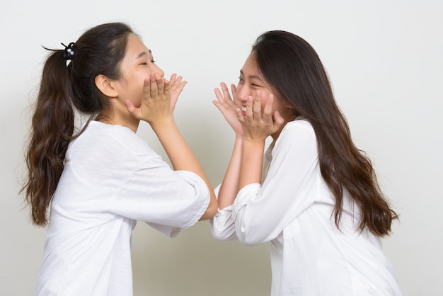 白い背景に対して一緒に友達として2人の若い美しい韓国人女性のスタジオショット