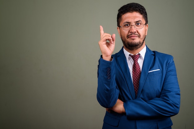 Studio shot van bebaarde zakenman pak dragen tegen gekleurd