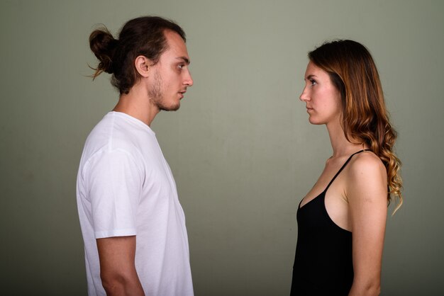 Studio shot van de jonge knappe man en jonge mooie vrouw samen tegen een gekleurde achtergrond