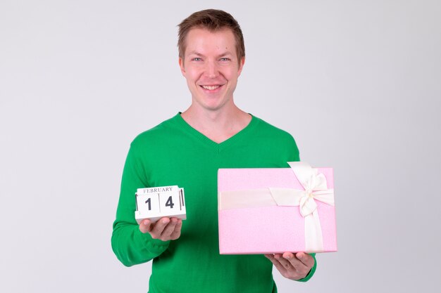 Studio shot van de jonge knappe man klaar voor valentijnsdag tegen witte achtergrond