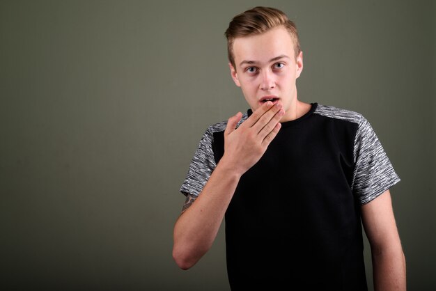 Studio shot van de jonge knappe man met blond haar tegen een gekleurde achtergrond