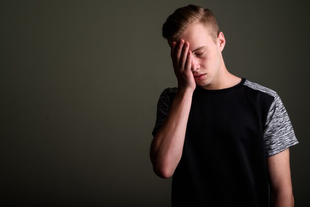 Studio shot van de jonge knappe man met blond haar tegen een gekleurde achtergrond