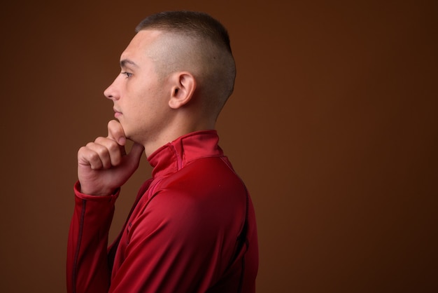 Studio shot van de jonge knappe man met kort haar tegen bruin