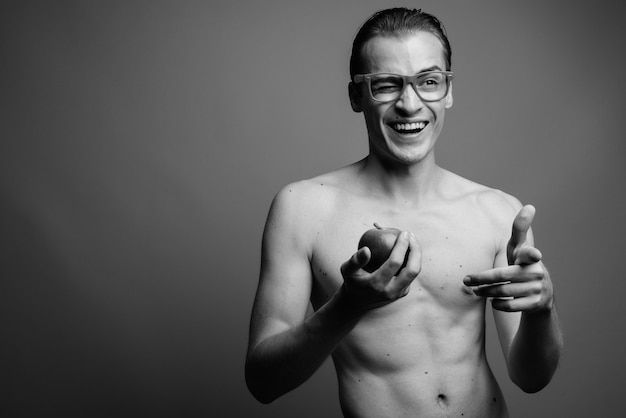 Studio shot van de jonge knappe man shirtless tegen grijze muur in zwart-wit