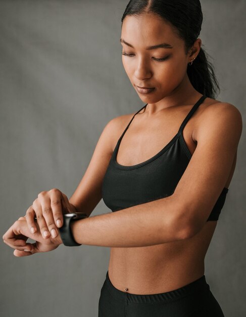 Studio shot van een vrouw in fitnesskleding die naar een slim horloge kijkt