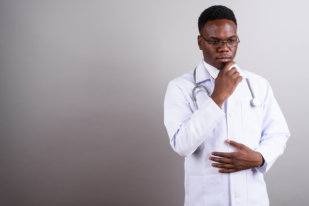 Studio shot van jonge Afrikaanse man arts bril dragen tegen witte achtergrond