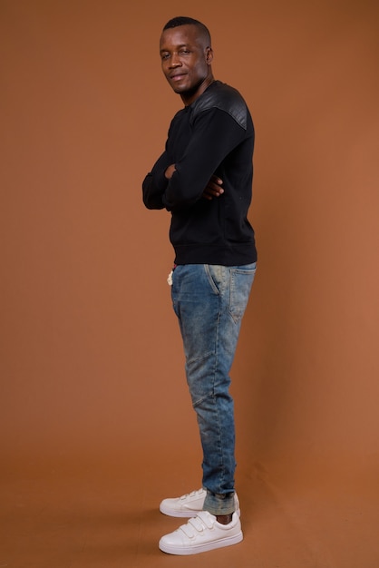 Studio shot van jonge Afrikaanse man tegen bruine achtergrond