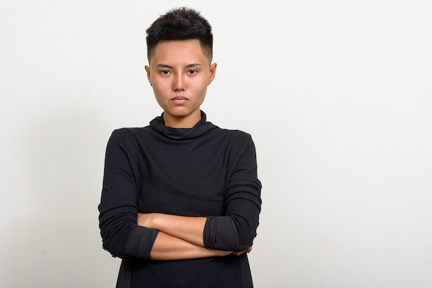 Studio shot van jonge Aziatische lesbische vrouw met kort haar tegen een witte achtergrond