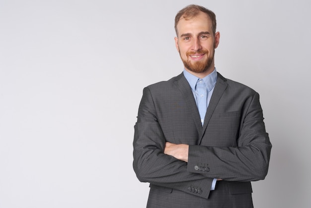 Foto studio shot van jonge bebaarde zakenman pak tegen wit dragen