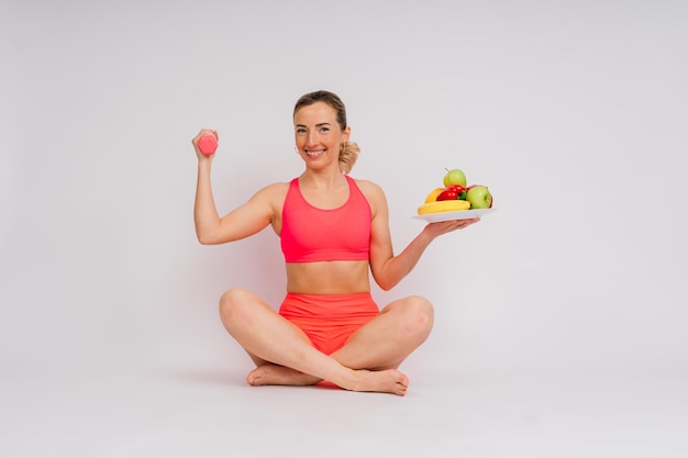 Studio shot van jonge fitness vrouw in een sportkleding met groene appel, fruit, groenten.