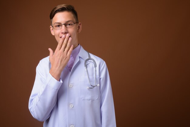 Studio shot van jonge knappe dokter tegen bruine achtergrond