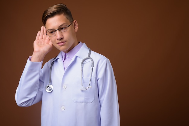 Studio shot van jonge knappe dokter tegen bruine achtergrond