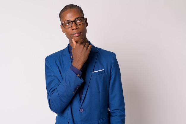 Studio shot van jonge knappe kale Afrikaanse zakenman in pak met bril tegen witte achtergrond