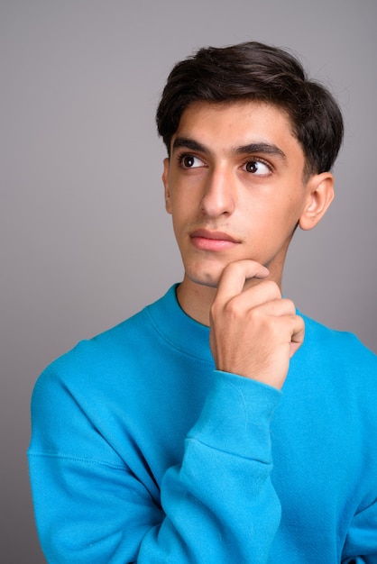 Studio shot van jonge knappe Perzische tiener tegen een grijze achtergrond