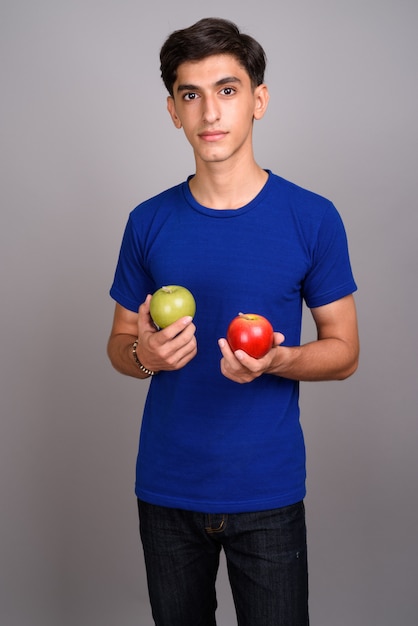 Studio shot van jonge knappe Perzische tiener tegen een grijze achtergrond