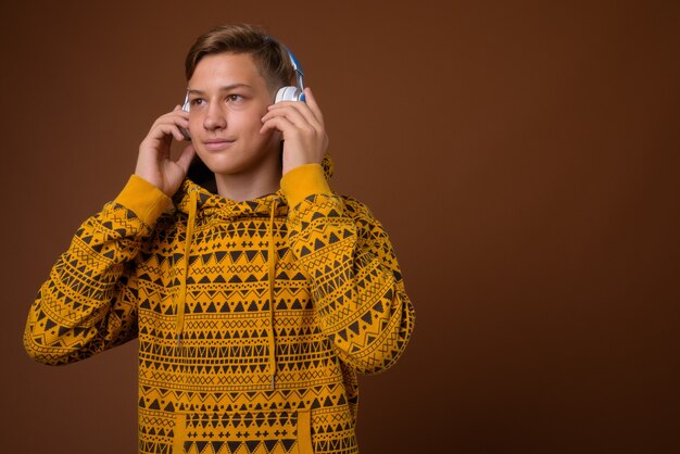 Studio shot van jonge knappe tiener tegen bruine CHTERGRO