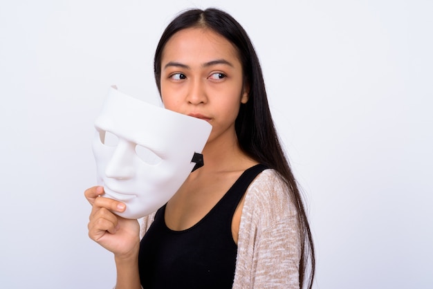 Studio shot van jonge mooie Aziatische vrouw tegen witte achtergrond