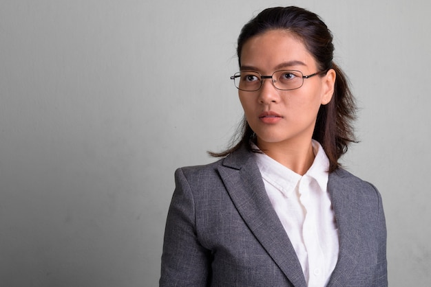 Studio shot van jonge mooie Aziatische zakenvrouw dragen bril tegen wit