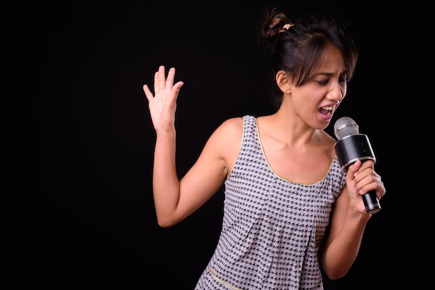 Studio shot van jonge mooie Filipijnse vrouw tegen zwarte achtergrond