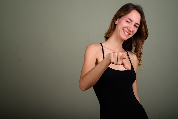 Studio shot van jonge mooie vrouw, gekleed in mouwloze top tegen een gekleurde achtergrond