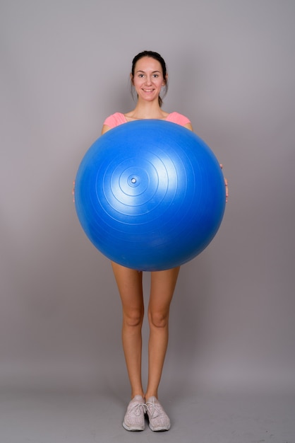 Foto studio shot van jonge mooie vrouw klaar voor sportschool tegen grijs