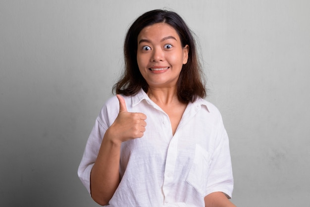 Studio shot van jonge mooie vrouw met kort haar tegen wit