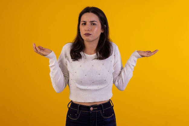 Studio shot van jonge vrouw in wit overhemd op gele achtergrond met verschillende gezichtsuitdrukkingen