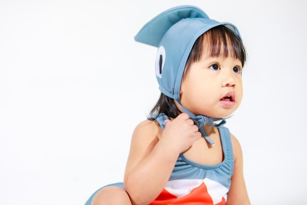 Studio shot van kleine mooie kleuterschool Aziatische baby meisje dochter model in schattige grijze haai kostuum badpak outfit zittend op een witte achtergrond