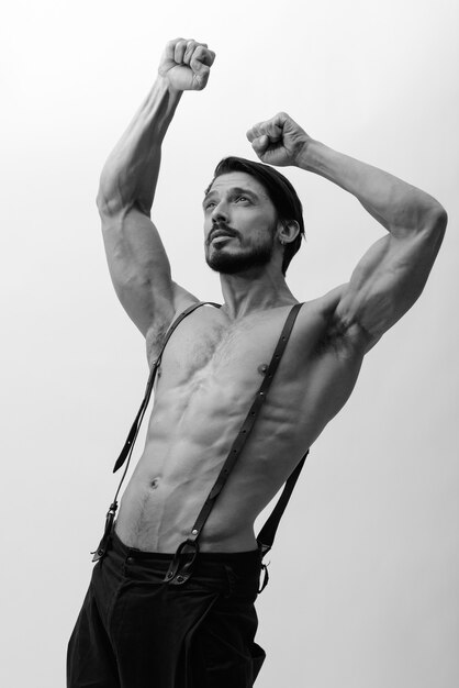 Studio shot van knappe man beide armen buigen terwijl shirtless opzoeken