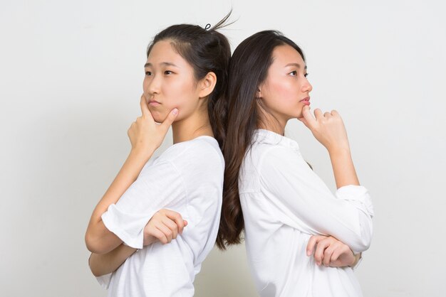 Studio shot van twee jonge mooie Koreaanse vrouwen als vrienden samen tegen een witte achtergrond