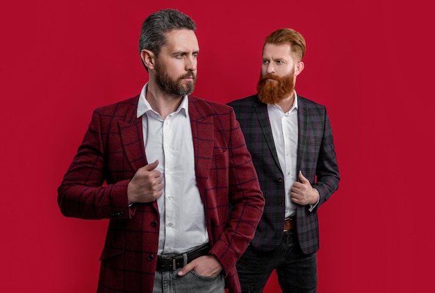 Studio shot van twee ongeschoren mannen in formalwear jassen mannen in formalwear geïsoleerd op bordeaux