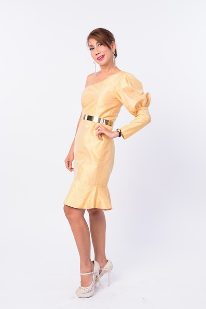 Studio shot van volwassen Aziatische zakenvrouw draagt gele jurk geïsoleerd tegen een witte achtergrond