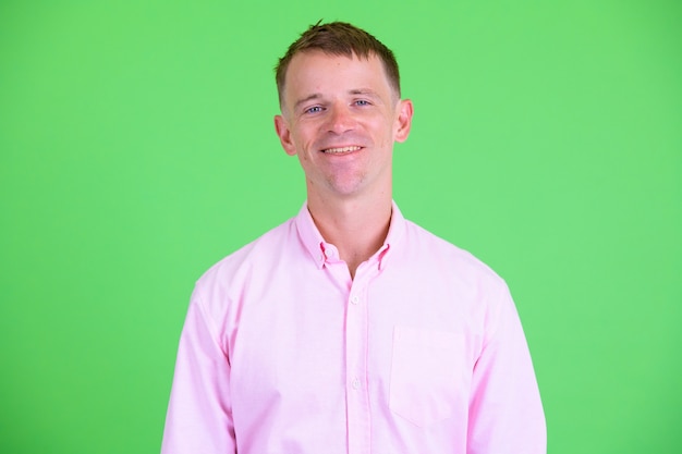 Studio shot van zakenman roze shirt dragen tegen een groene achtergrond