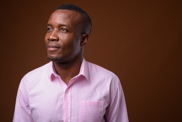 Studio shot of young African businessman against brown background