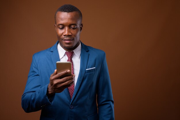 Studio shot of young African businessman against brown background