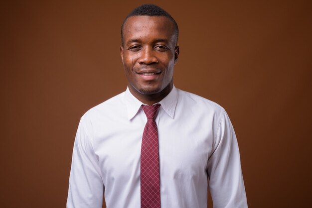 Studio shot of young African businessman against brown background