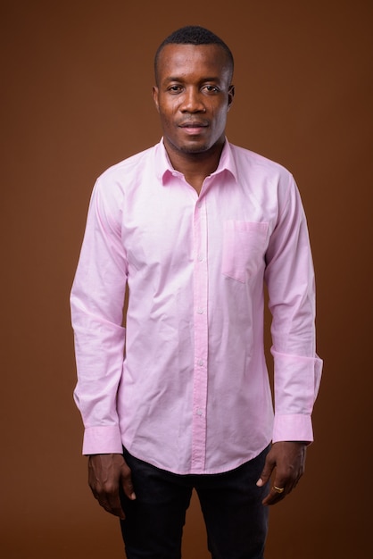 Studio shot of young African businessman against brown background