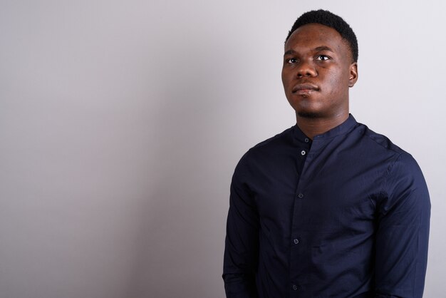 Studio shot of young African businessman wearing blue shirt against white background