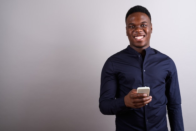 Studio shot of young African businessman with mobile phone against white background