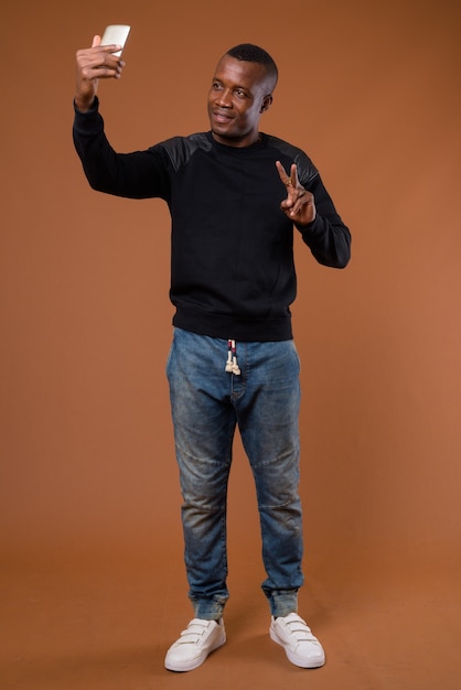 Studio shot of young African man against brown background