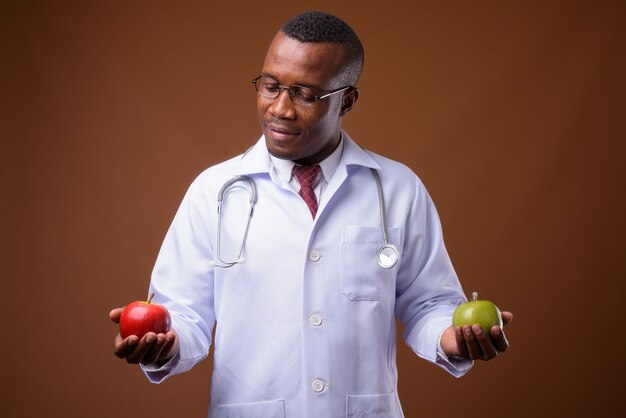 Studio shot of young African man doctor against brown background