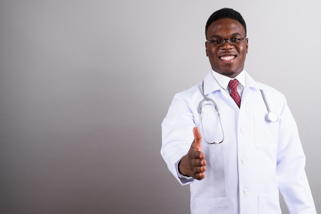白い背景に眼鏡をかけている若いアフリカ人男性医師のスタジオショット
